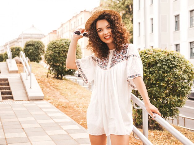Mooi lachende model met afro krullen kapsel gekleed in zomer hipster witte jurk.