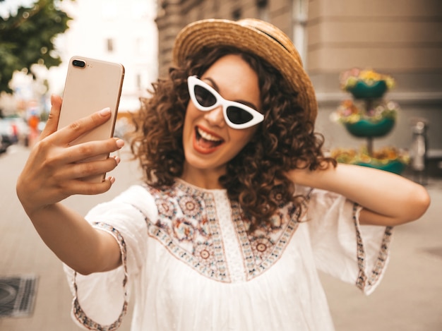 Mooi lachende model met afro krullen kapsel gekleed in zomer hipster witte jurk.