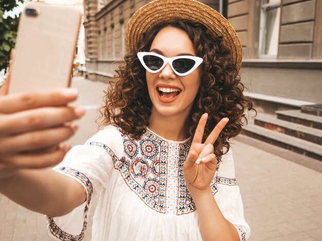 Mooi lachende model met afro krullen kapsel gekleed in zomer hipster witte jurk.