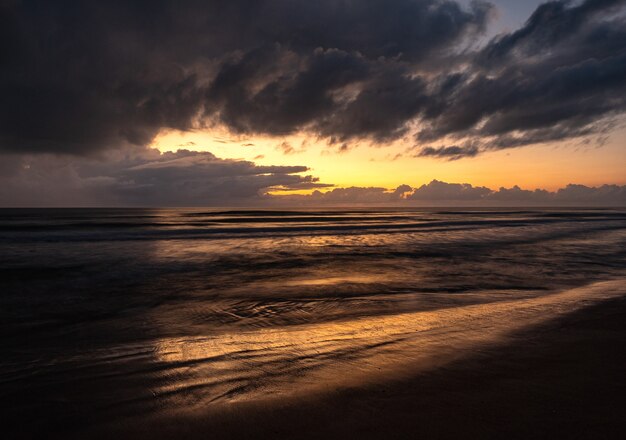 Mooi landschap van een golvende zee onder een bewolkte hemel bij zonsopgang
