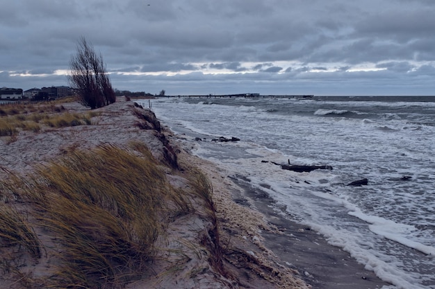 Gratis foto mooi landschap van een met gras begroeide heuvel aan zee tijdens zonsondergang