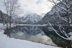 Gratis foto mooi landschap van het plansee-meer, omringd door hoge besneeuwde bergen in heiterwang, oostenrijk