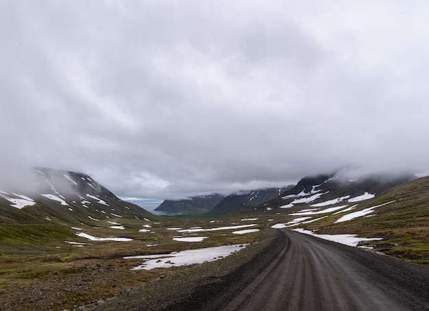 Gratis foto mooi landschap van heuvels onder de bewolkte grijze hemel in ijsland