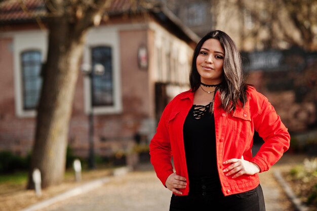 Mooi latino-modelmeisje uit Ecuador draagt een zwart en rood jasje op straat