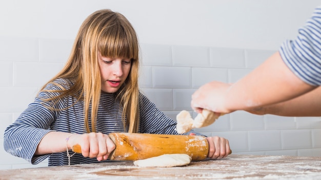 Mooi meisje dat deeg met concentratie uitrolt