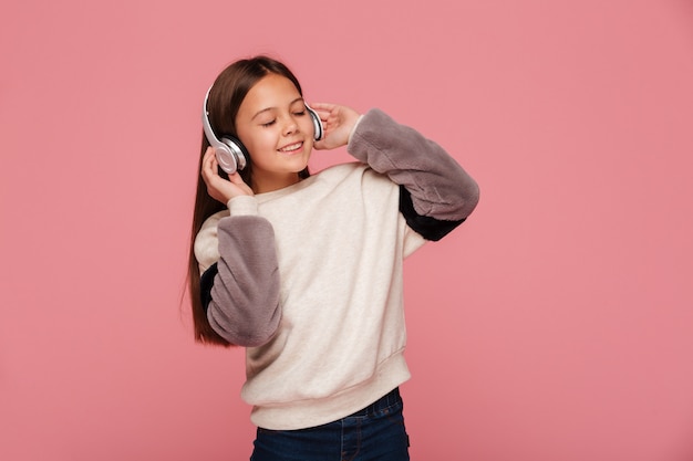 Mooi meisje dat van geïsoleerde muziek in hoofdtelefoons geniet