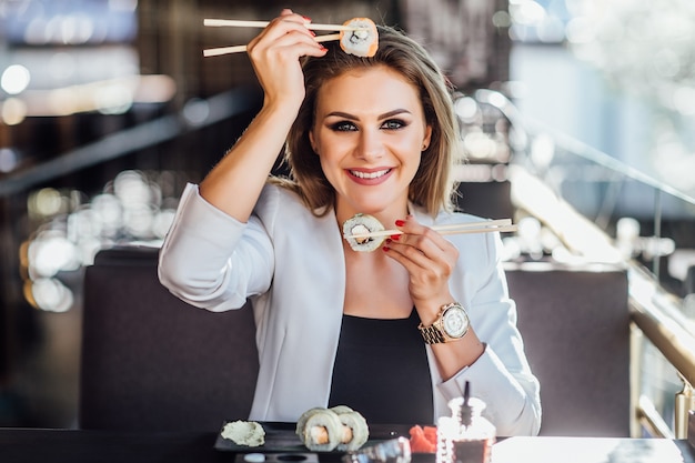 Mooi meisje genieten van sushi in een zomerterras van moderne caffe.