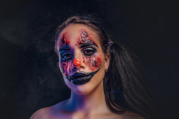 Mooi meisje heeft een zeer griezelige make-up voor Halloween in de rol van griezelige clown.