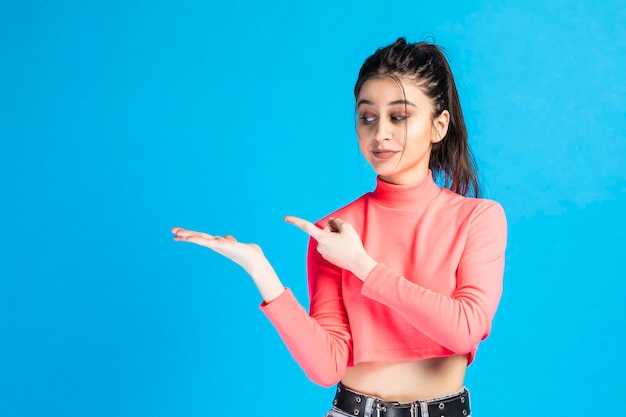 Mooi meisje houdt haar hand open in de lucht en wijst naar die plek