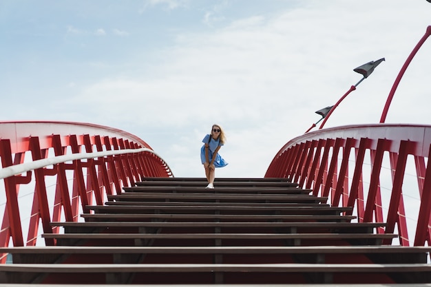 mooi meisje in een blauwe jurk die zich voordeed op de brug