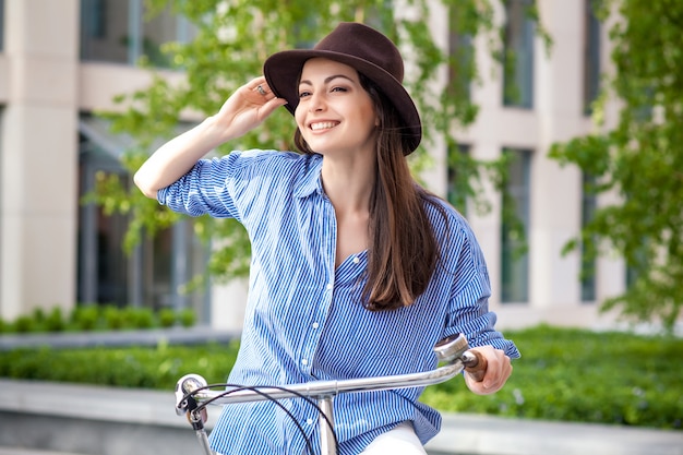 Mooi meisje in hoed die een fiets berijden bij straat