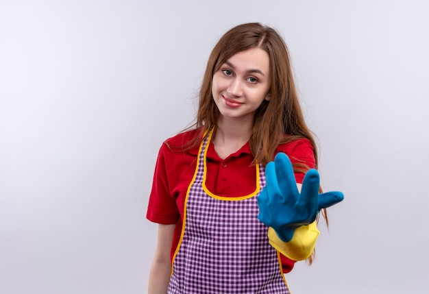 Mooi meisje in schort en rubberen handschoenen glimlachend maken komen in gebaar met hand