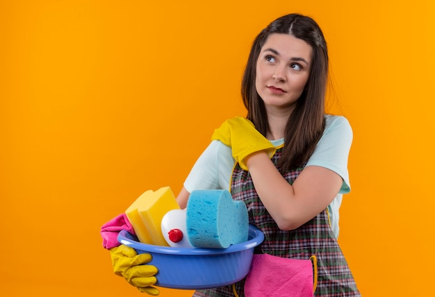 Mooi meisje in schort en rubberen handschoenen met bekken met reinigingsgereedschap schouder gevoel pijn aan te raken