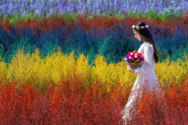 Mooi meisje in witte jurk, zittend in de velden van de regenboogbloemen van cutter, chiang mai