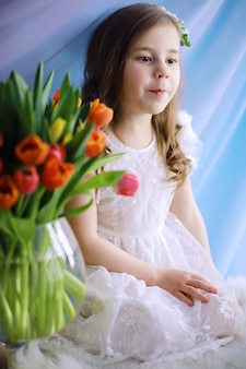 Mooi meisje in witte jurken met een prachtig boeket van de eerste tulpen. internationale vrouwendag. meisje met tulpen.