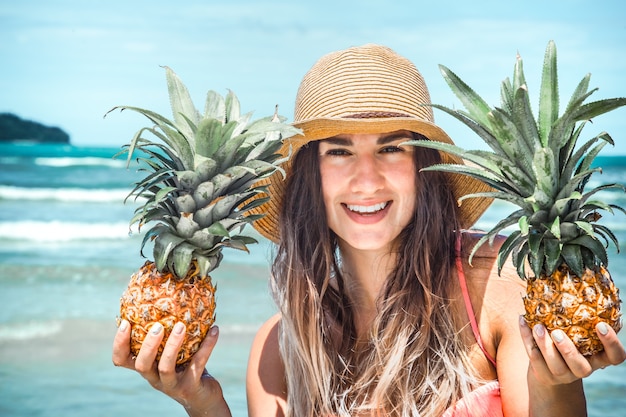 mooi meisje met ananas op een exotisch strand, een gelukkig humeur en een mooie glimlach