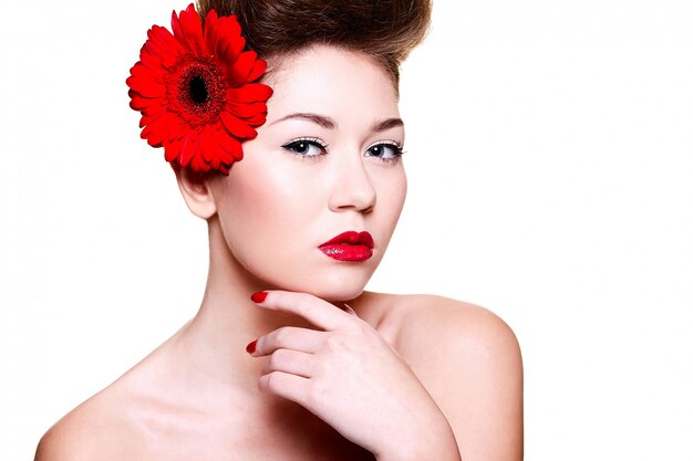 mooi meisje met rode lippen en nagels met een bloem op haar haar