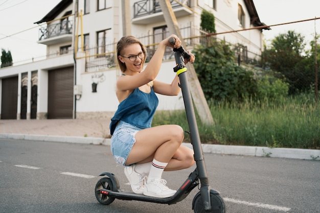 Gratis foto mooi meisje rijden op een elektrische scooter in de zomer op straat