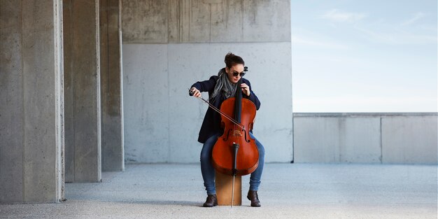 mooi meisje speelt cello met passie in een concrete omgeving