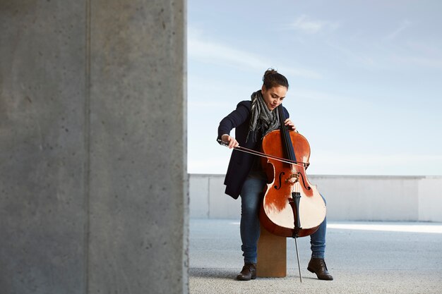 mooi meisje speelt cello met passie in een concrete omgeving