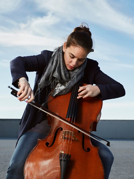 mooi meisje speelt cello met passie in een concrete omgeving