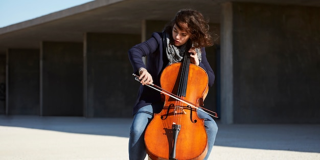 Gratis foto mooi meisje speelt cello met passie in een concrete omgeving