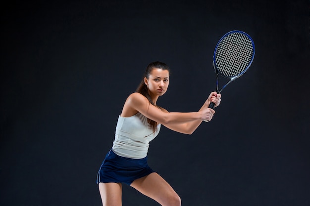 Mooi meisje tennisspeler met een racket op donkere achtergrond