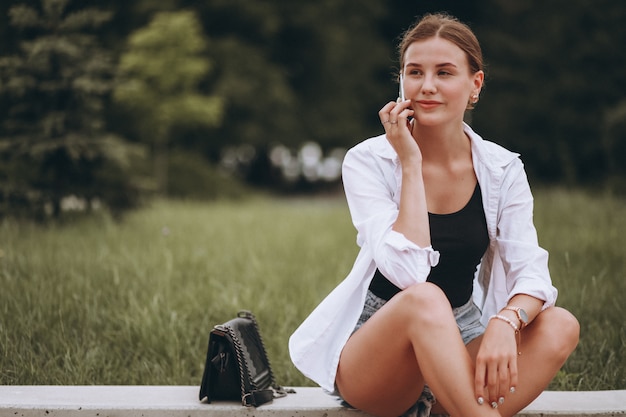 Gratis foto mooi meisje zit in de straat en het gebruik van de telefoon