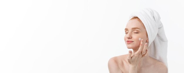 Mooi model die kosmetische roombehandeling op haar gezicht op wit toepassen