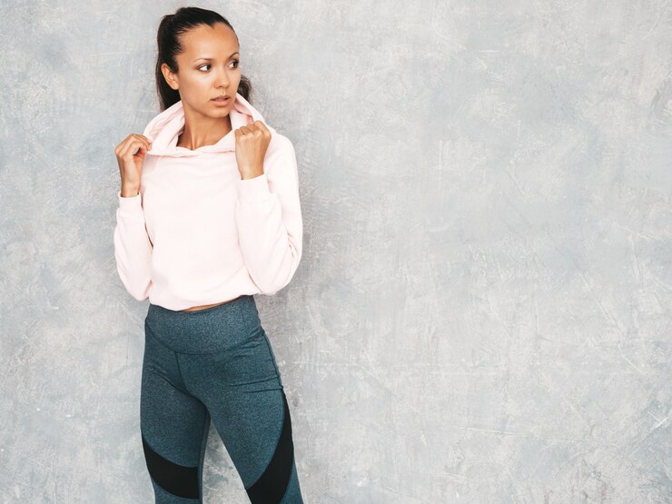 Gratis Foto mooi model met perfect gebruinde lichaam. vrouwelijke poseren in de studio in de buurt van grijze muur