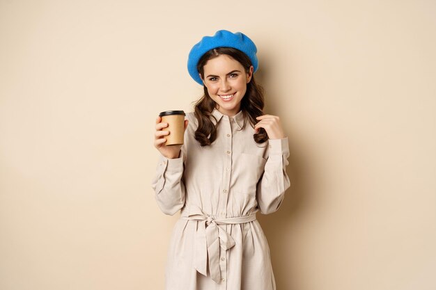 Mooi modern meisje poseren met afhaal kopje koffie drinken uit herbruikbare beker uit café en pos...