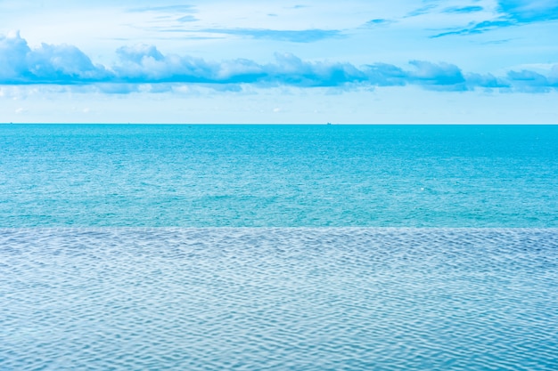 Mooi openlucht oneindig zwembad in hoteltoevlucht met overzeese oceaanmening en witte wolken blauwe hemel