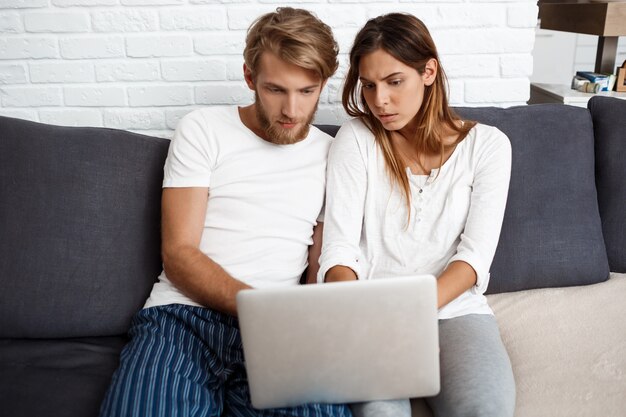 Mooi paar dat laptop zitting op bankhuis bekijkt.