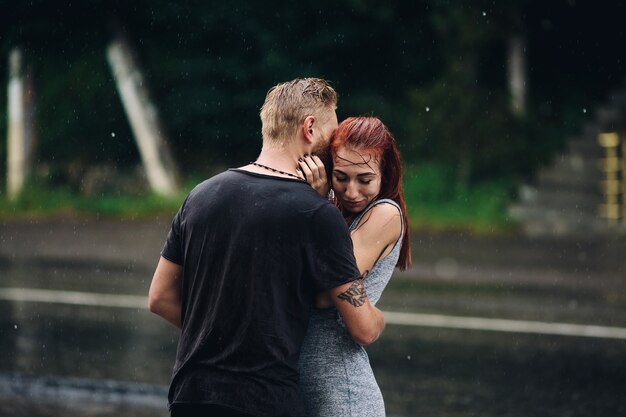 Mooi paar knuffelen buiten in de regen