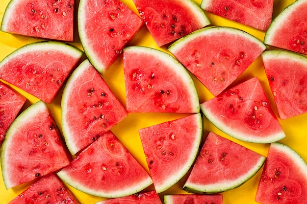 Gratis foto mooi patroon met verse watermeloen plakjes op gele heldere achtergrond. bovenaanzicht.