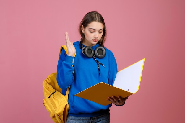 Mooi schoolmeisje dat staat te lezen en hand te antwoorden