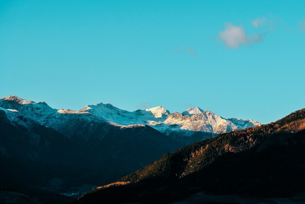 Mooi schot van beboste heuvels en besneeuwde berg in de verte met blauwe hemel