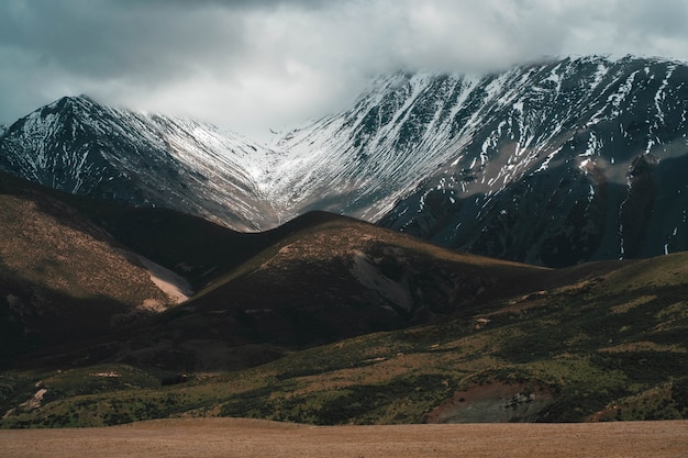 Mooi schot van besneeuwde rotsachtige bergen en heuvels onder een mistige bewolkte hemel