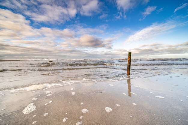 Mooi schot van de zee die onder een blauwe bewolkte hemel naar de kust komt