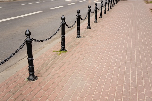 Gratis foto mooi schot van een baksteenstoep met zwarte moderne palen van het veiligheidsmetaal