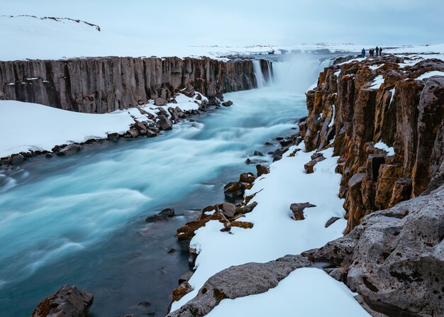 Mooi schot van een rivier in een besneeuwde rotsachtige ondergrond