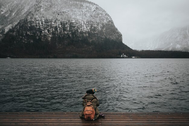 Mooi schot van een vrouwenzitting op een houten dok voor het water op een mistige de winterdag