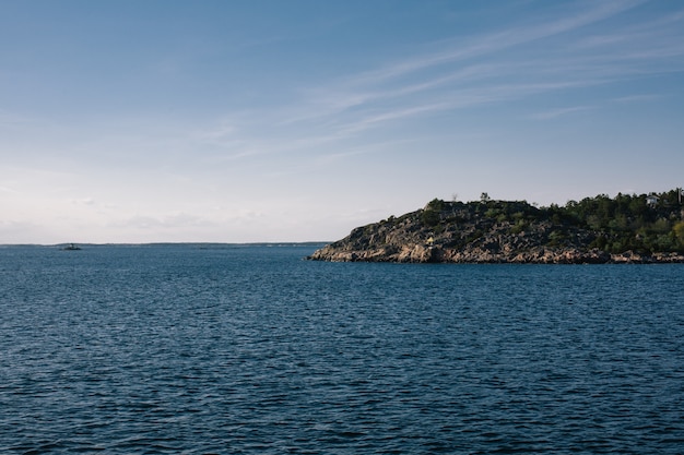 Mooi schot van een zee met een berg in de verte onder een heldere hemel