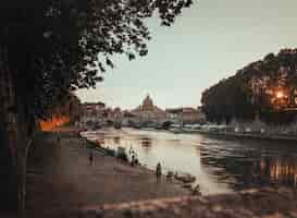 Gratis foto mooi schot van een zwarte concrete weg naast het lichaam van waterin rome, italië tijdens zonsondergang