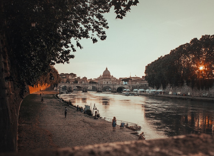 Gratis Foto mooi schot van een zwarte concrete weg naast het lichaam van waterin rome, italië tijdens zonsondergang