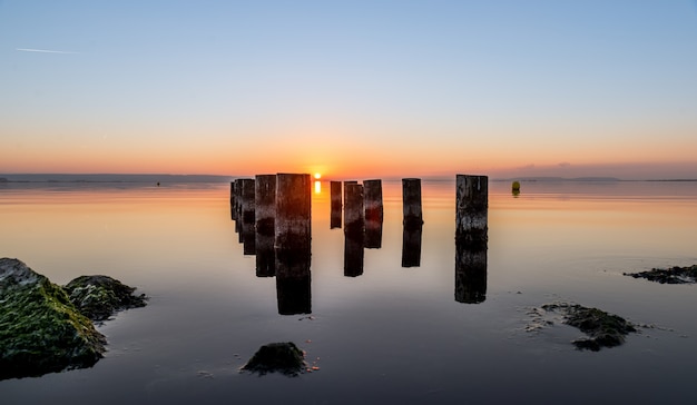 Gratis foto mooi schot van versleten pijlerpijlers op een watermassa tijdens zonsondergang. perfect voor een behang