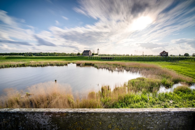 Mooi shot van een klein meer omgeven door groen onder een bewolkte hemel