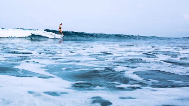 mooi surfermeisje die op een raad berijden