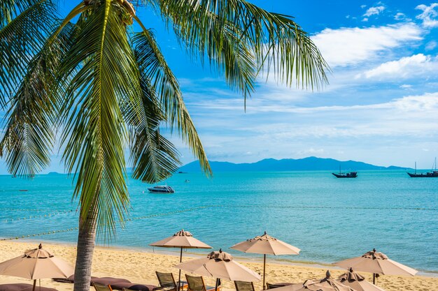 Mooi tropisch strand met kokospalm en parasols