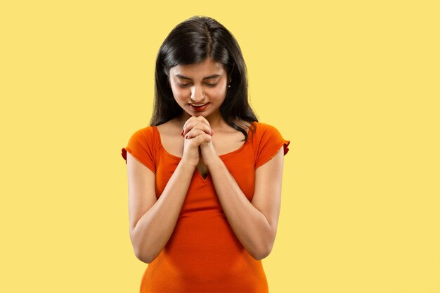 Mooi vrouwelijk geïsoleerd portret van halve lengte. Jonge emotionele Indiase vrouw in jurk bidden of zorgen maken. Negatieve ruimte. Gelaatsuitdrukking, concept van menselijke emoties.